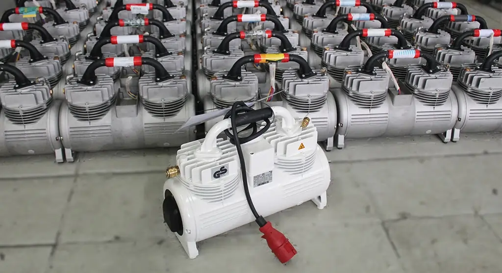 Reihe von grauen Kompressoren mit einem einzelnen weißen Kompressor im Vordergrund.