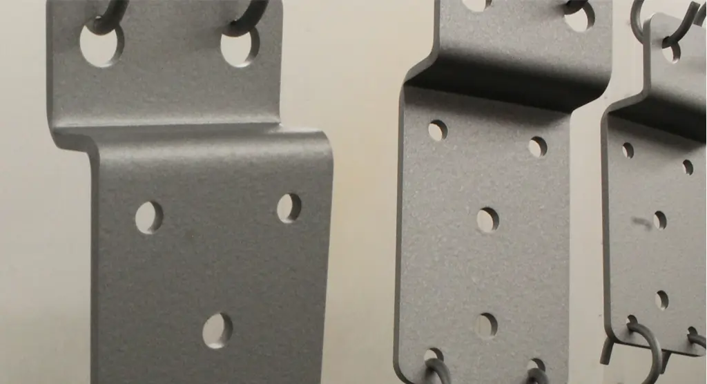 Nahaufnahme von lackierten Metallteilen, die zum Trocknen aufgehängt sind.