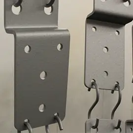 Nahaufnahme von lackierten Metallteilen, die zum Trocknen aufgehängt sind.